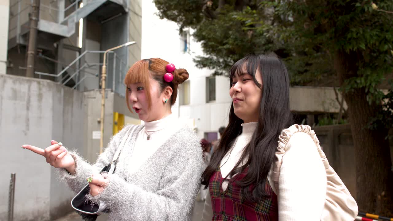 Dos amigos ríen y señalan una máquina expendedora colorida en una calle de la ciudad de Tokio