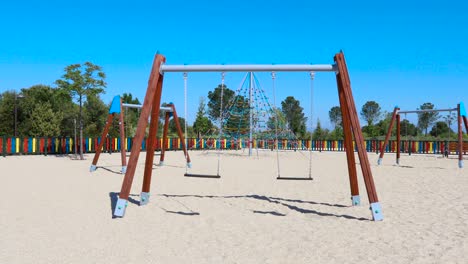 motion shot approaching double empty swings swinging in playground