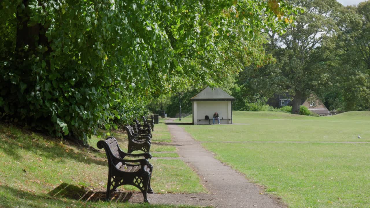 Peaceful park path with benches and gazebo in lush green Oakham setting