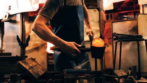 Mid-section-of-glassblower-shaping-a-molten-glass