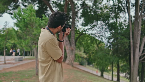 professional man photographing green park at weekend walk close up. guy looking