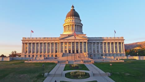 La-Bandera-Estadounidense-Ondea-Lentamente-En-El-Edificio-Del-Capitolio-Del-Estado-De-Utah,-Iluminada-Por-El-Sol-Poniente
