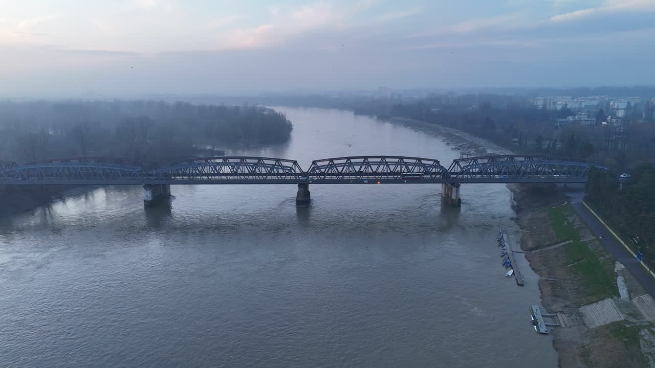 Vista aerea di un treno pendolari che attraversa il ponte sul fiume Po a Cremona, in Lombardia, Italia, che mette in risalto le infrastrutture ferroviarie, la mobilità urbana e il trasporto quotidiano sul fiume italiano più grande