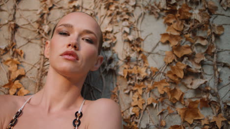 woman posturing autumn leaves on wall close up. sensual model looking camera