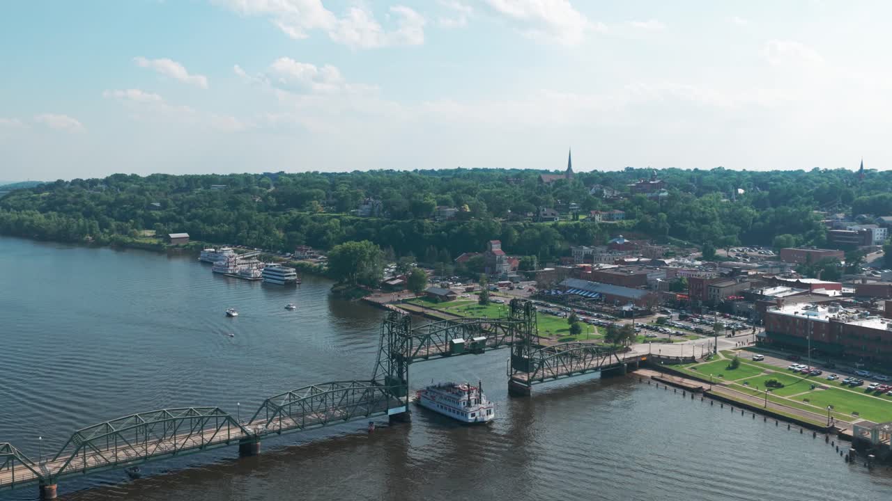 Aerial wide panning shot of a riverboat traveling beneath the St. Croix River Lift Bridge in Stillwater, Minnesota. 4K