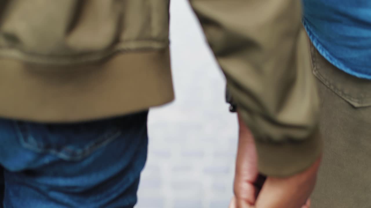 거리를 걸어가는 동안 손을 잡고 있는 아프리카계 미국인 커플의 클로즈업 보기
