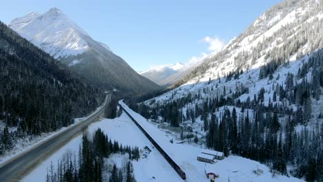 freight train traveling through snowy forests and majestic mountains in revelstoke, british columbia: winter wonderland from above