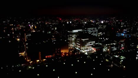 Night-cityscape-with-illuminated-buildings-and-dark-sky,-vibrant-urban-nightlife,-expansive-view