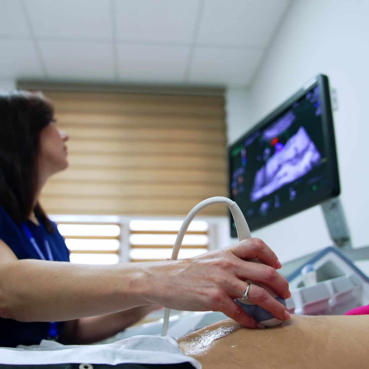 Brunette doctor checks pregnant woman on ultrasound machine. Obstetrician checking the health of mom and future baby. Low angle view