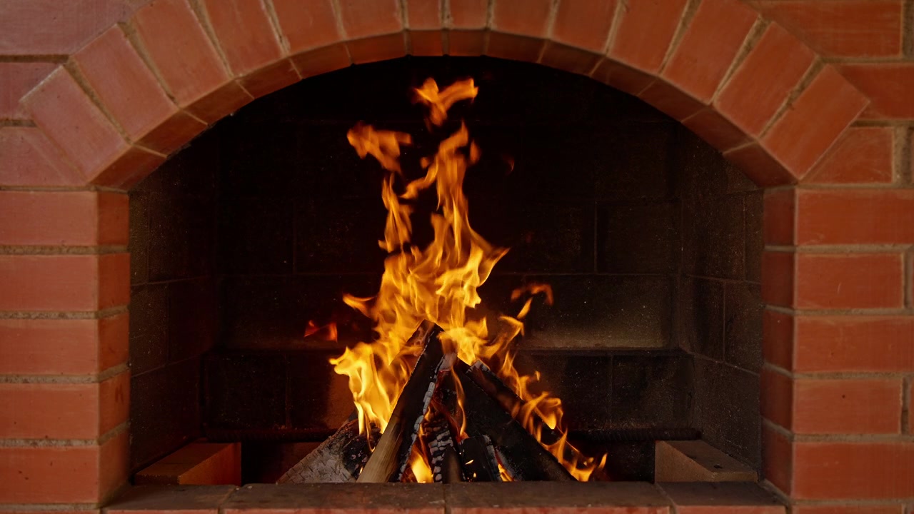 Fuego brillante ardiendo en una chimenea de ladrillo rojo