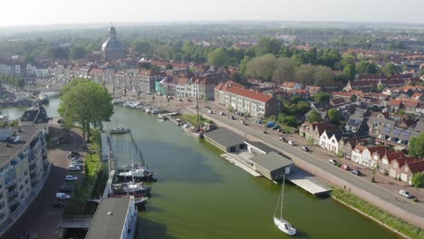 aerial shot of a sailboat sailing on a waterway through the historical town of middelburg, the netherlands, on a sunny summer evening