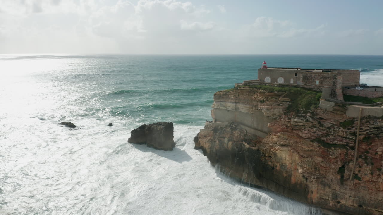 Aerial of a beautiful old fortress on cliff surrounded by a wild sea