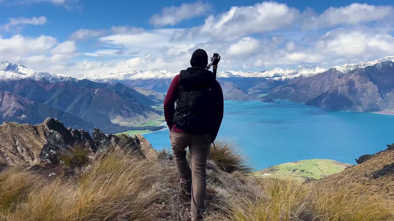 Male hiker overlooking scenic Lake Hawea, embracing nature and solitude