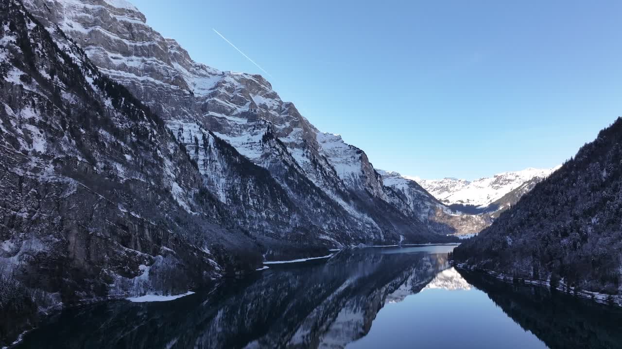 Snowy mountain landscape with lake reflection in Klöntalersee, Glarus, Switzerland