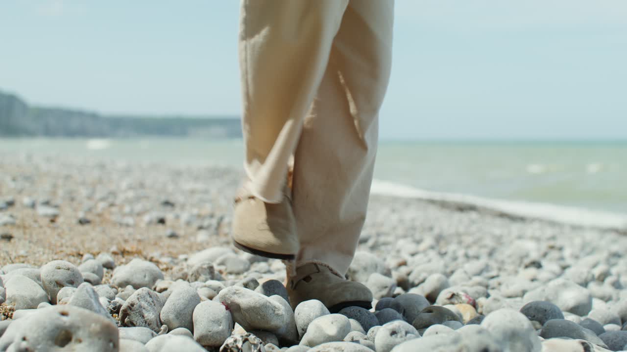 persona caminando por una playa de guijarros