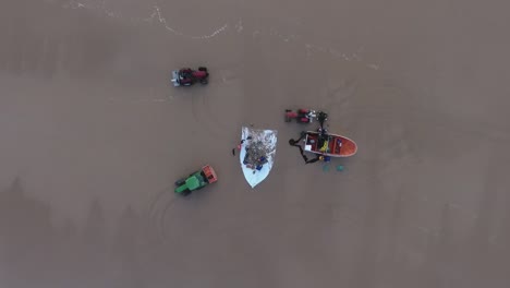 aerial zoom out showing a group of traditional portuguese fishermen taking in the catch of the day