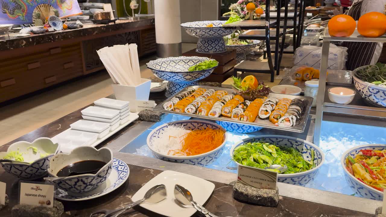 A colorful buffet setup with sushi, salads, and fruits in a well-lit Asian restaurant environment