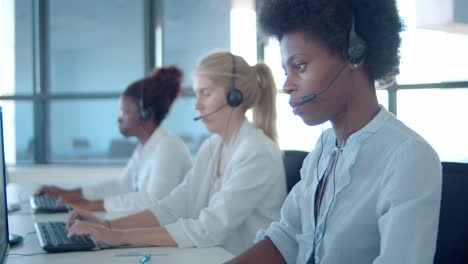 serious diverse consultants in headsets working at computers