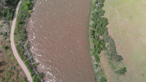 Draufsicht-Auf-Die-Stark-Schlammige-Fließende-Kurve-Des-Colorado-River-In-Moab-Mit-Einer-Parallelen-Straße