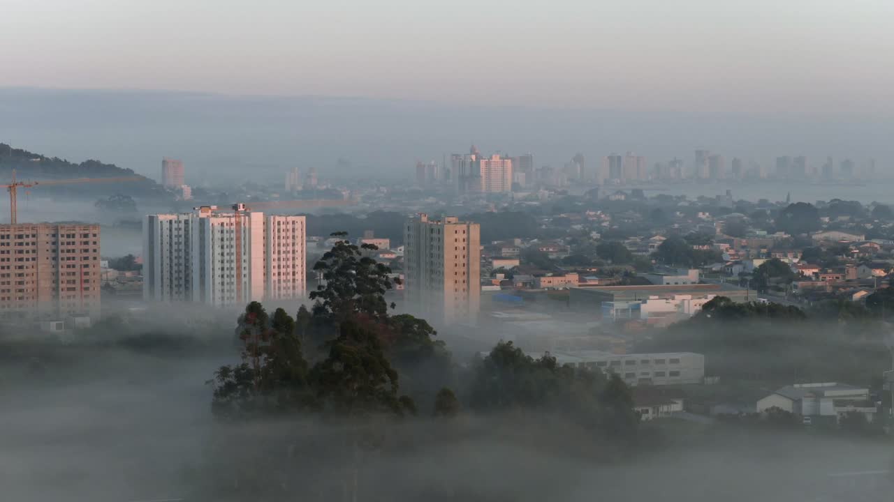 Cityscape view of hotel buildings emerging through early morning sunrise fog in Penha city, Santa Catarina, Brazil