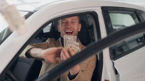 Handsome-young-man-sitting-in-the-car-scattering-dollar-bills