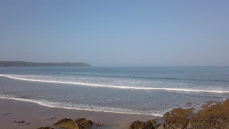 right to left pan of waves crashing against a beautiful sandy beach in slow motion