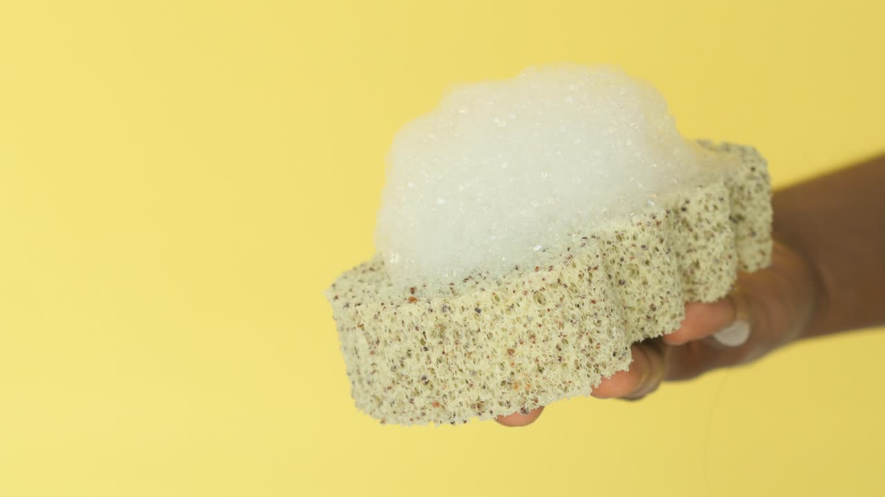 Sponge with soap and bubbles being held in a hand