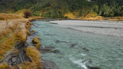 tilt up shot of slowly flowing stream at rees valley with giant mountains and clouds in backdrop