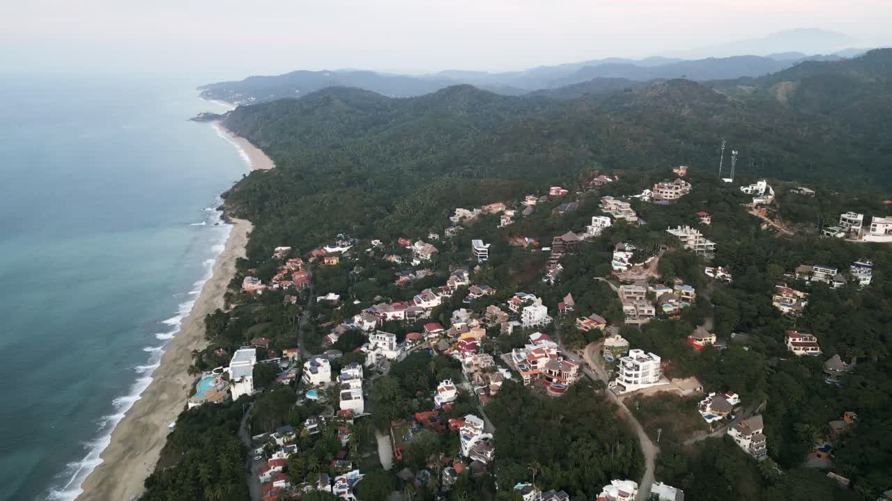 un avión no tripulado vuela sobre sayulita beach, un pueblo costero en la selva mexicana, colinas verdes, arena blanca y un paisaje marino azul prístino en el océano pacífico latinoamericano.