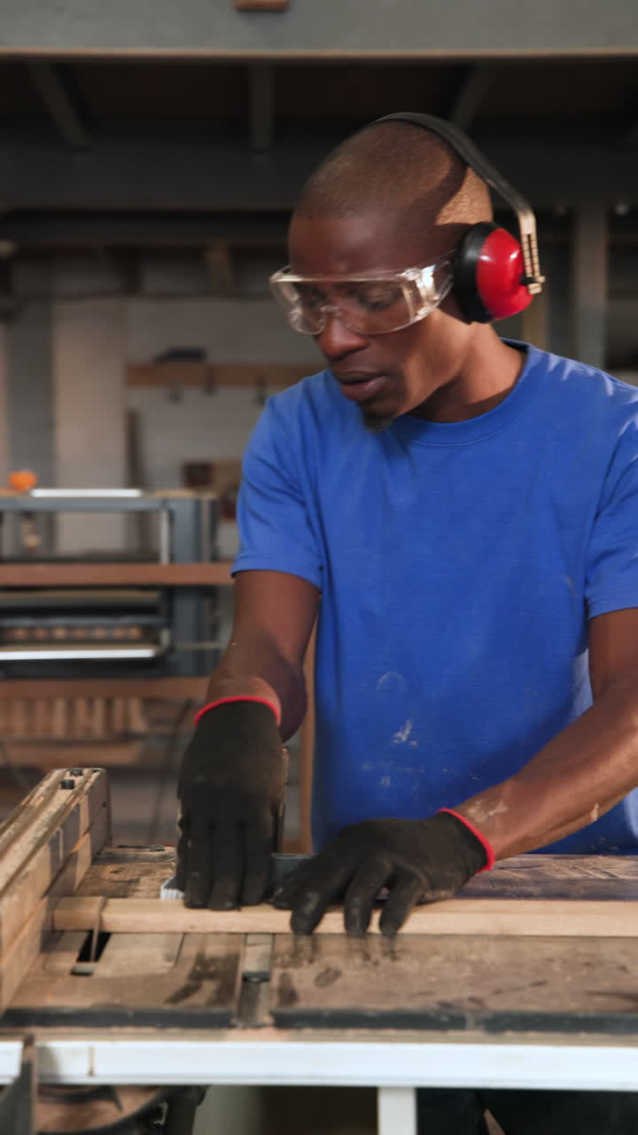 Vertical video: African American man approaching saw trimming planks in workshop for precision