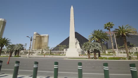 a ground level view of the luxor resort on the las vegas strip, with pedestrian guard posts in the foreground. it remains empty during the covid-19 pandemic. the delano hotel stands just to the left.