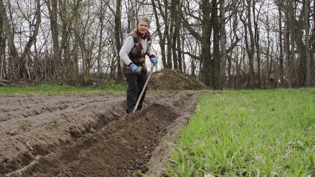 toma estática de una anciana jardinera trabajando a mano en un campo
