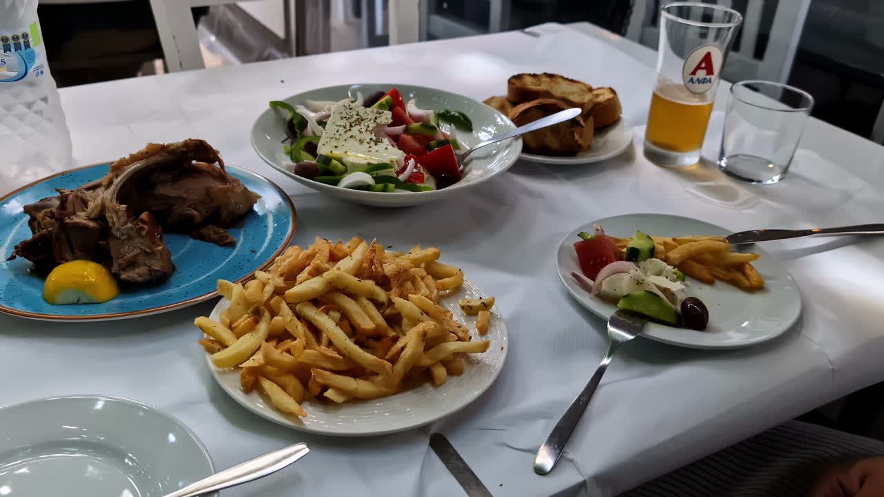 costillas de carne con papas fritas, ensalada de aceitunas mediterráneas servida, mesa de almuerzo de cerveza