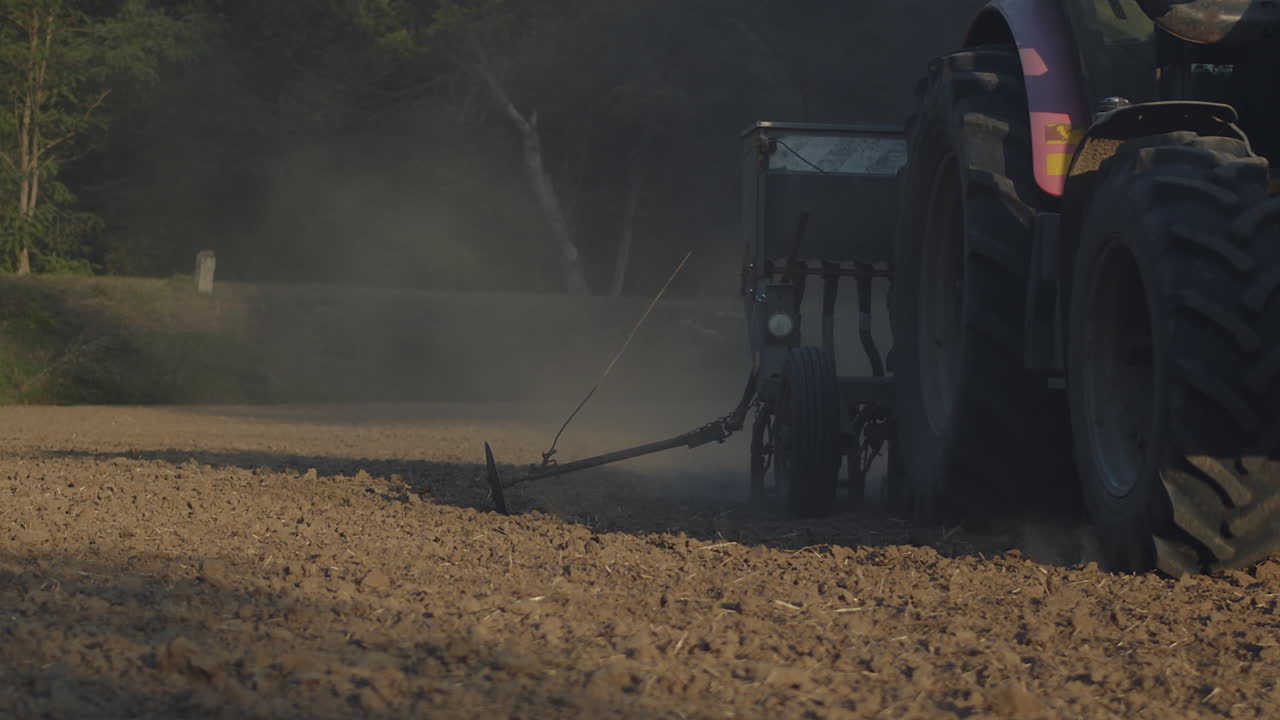 농장 트랙터는 갓 경작된 토양에 씨앗을 뿌린다