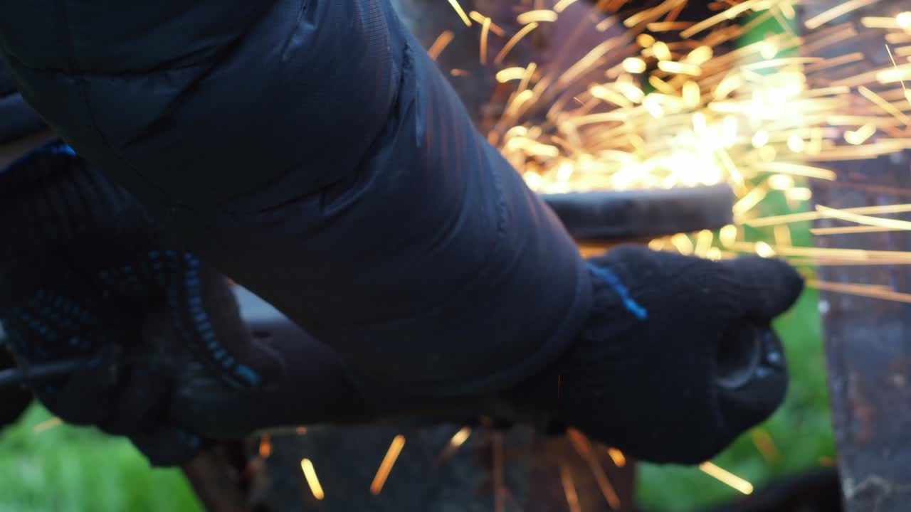 un hombre con guantes corta metal con un disco de corte. molinillo angular. trabajar con metal. pulverización de fuego. taller de reparación. mecánico de trabajos de ensamblaje mecánico