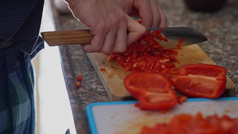 close-up man cutting red pepper on wooden board