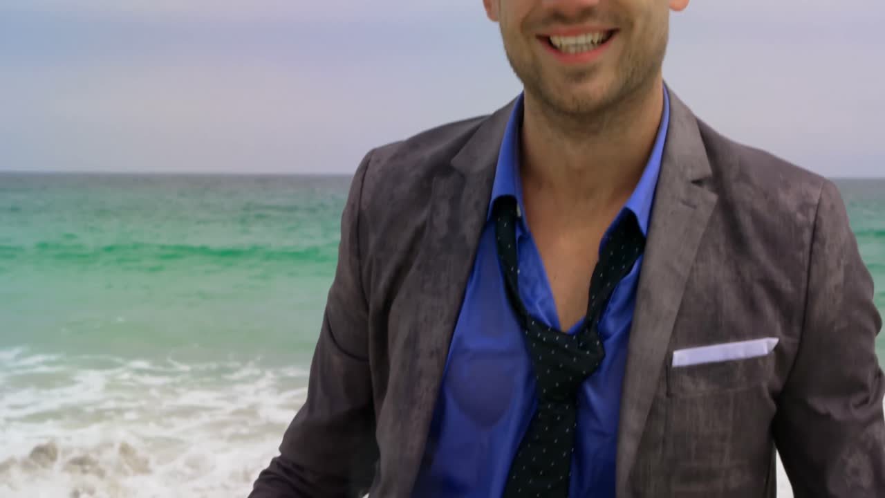 передний вид кавказского бизнесмена, стоящего с портфелем в море на пляже 4k