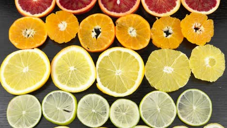 citrus fruits in a section on a black table. lemon, lime, orange, blood orange, mandarin