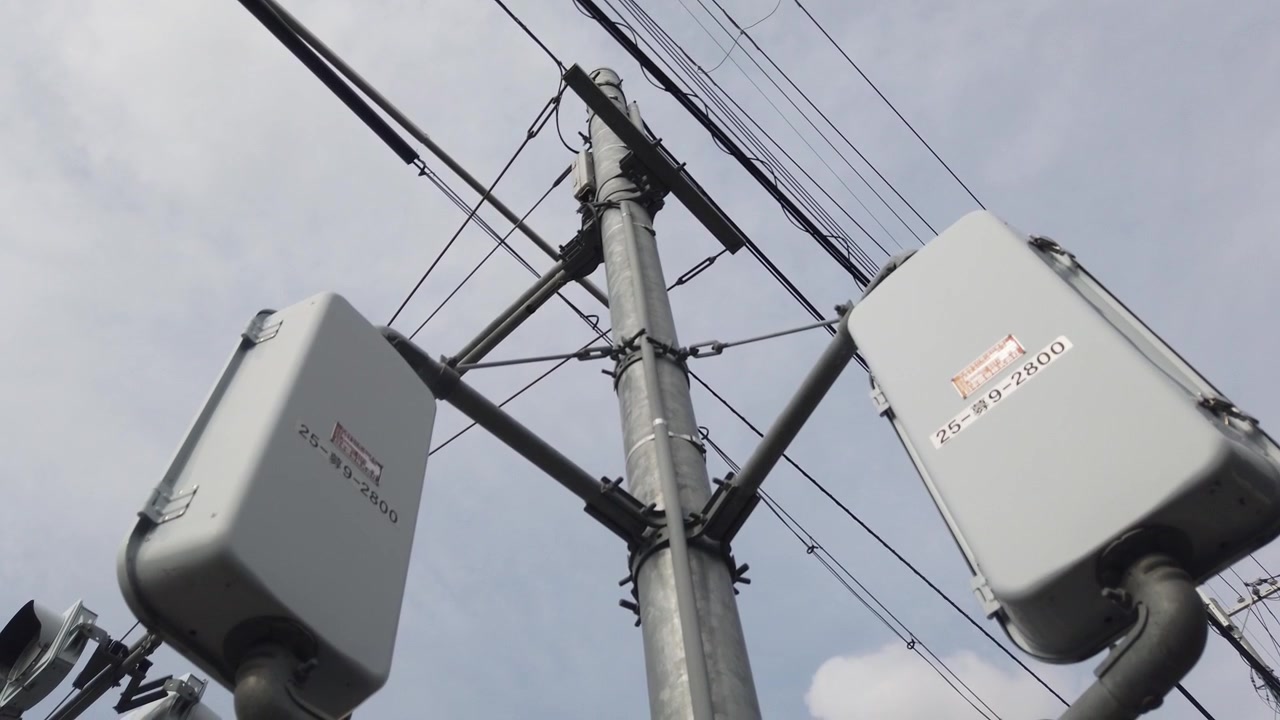 Low Angle View of Overhead Electricity Cables and Pedestrian Traffic Signal Housings in Japan