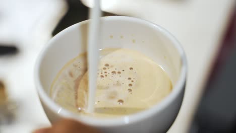 vertido de leche en un espresso doble