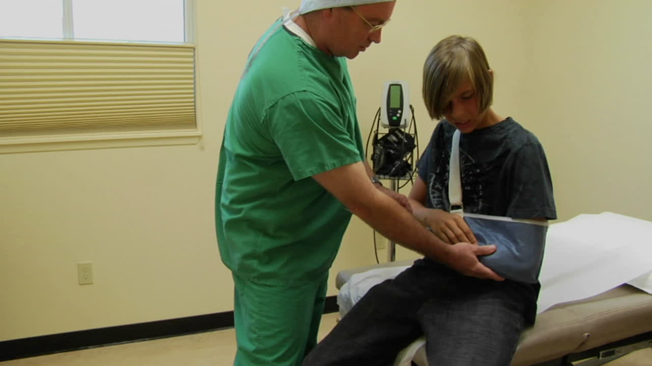 un médico examina el brazo herido de un adolescente