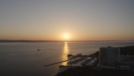 Sunset-time-above-the-ocean,-water-surface-in-slow-motion-at-sunset-time,-nature-background-static-shot-with-one-boat-sailing