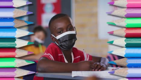 Animation-of-crayons-over-african-american-schoolboy-wearing-face-masks