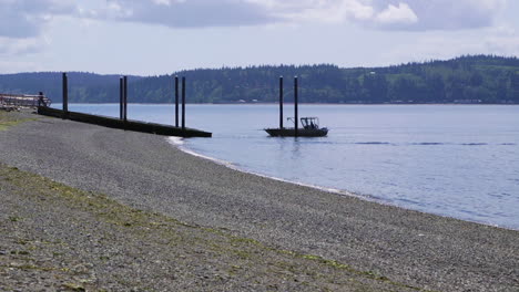 small, nondescript fishing boat cruising past beach at camano island state park, wa state