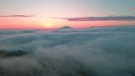 the sun rises above the clouds with a background of mountains and fog in the morning