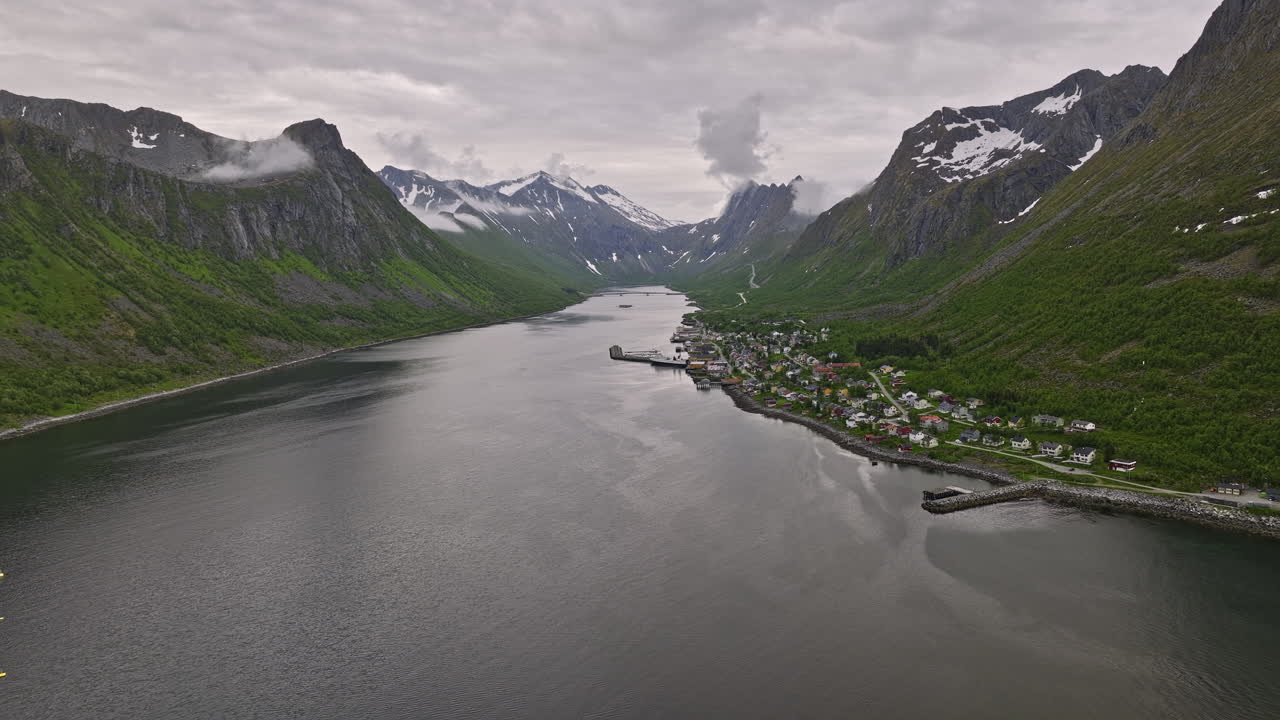 entrada aérea gryllefjord noruega v4 que captura un pequeño pueblo de pescadores con una jaula de red de acuicultura en un fiordo noruego rodeado de un hermoso paisaje montañoso - rodada con mavic 3 cine - junio de 2022