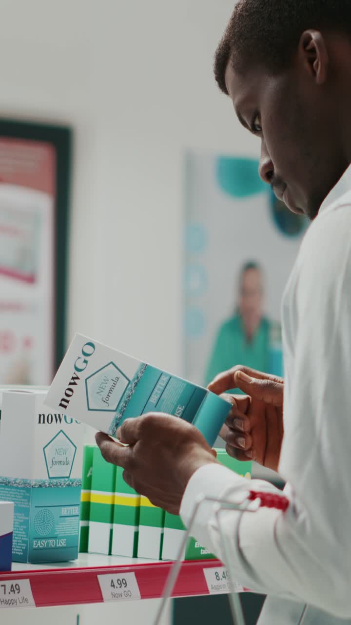 Vertical video: Young man looking at boxes of vitamins in pharmacy