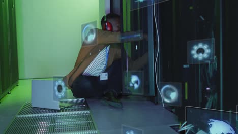 Animation-of-data-processing-on-screens-over-african-american-man-working-in-server-room