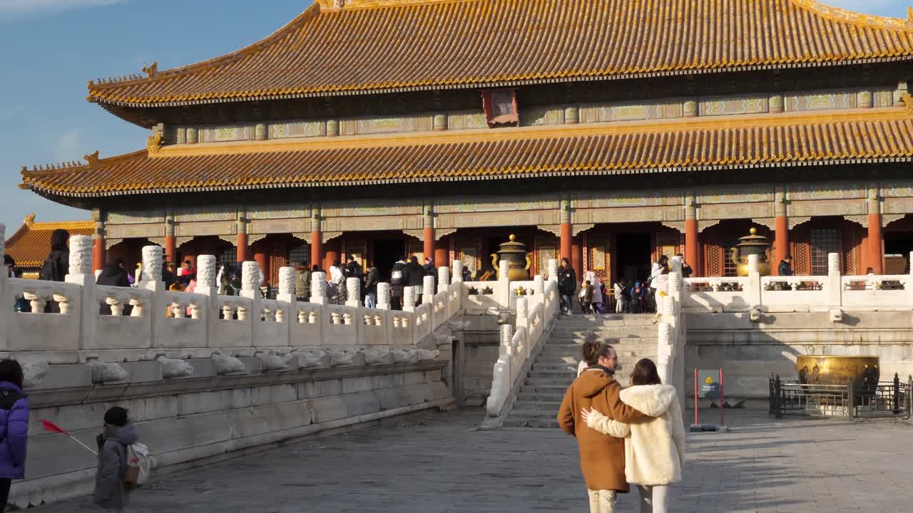 A man and woman stroll through a beautiful Chinese temple, enjoying the warm winter sunshine while discovering the architecture and surroundings together.