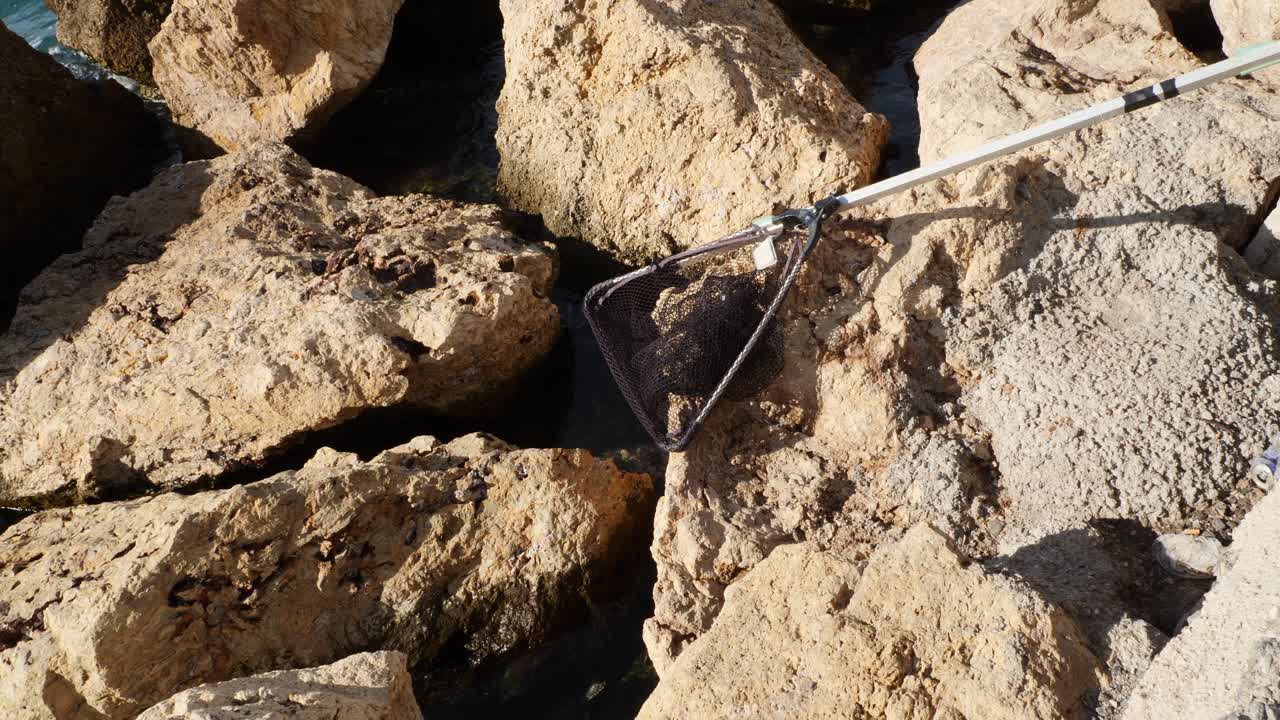 Guadino da pesca appoggiato sulle rocce